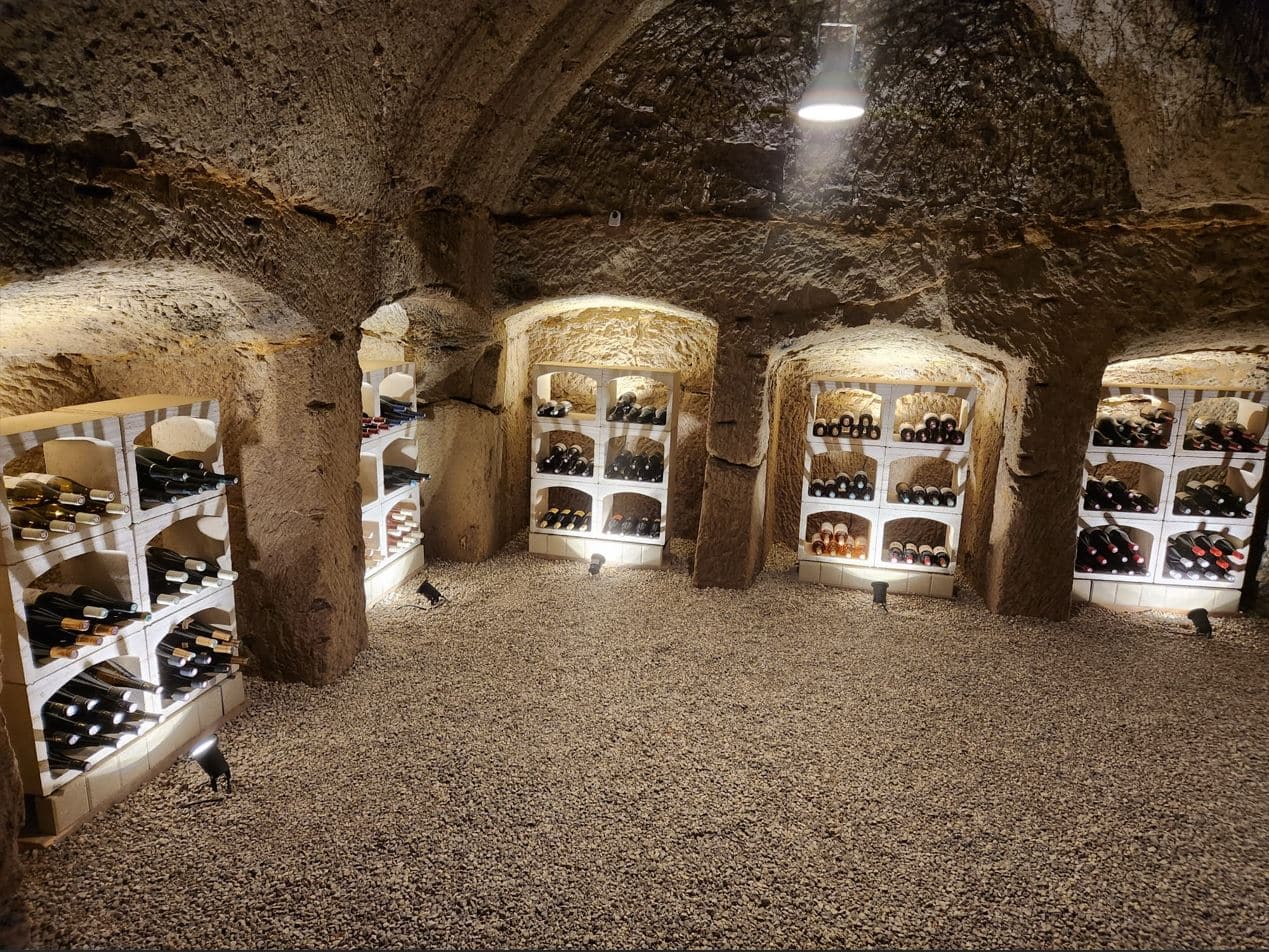 Casier à vin pour ranger les bouteilles dans une cave voûtée avec du gravier.